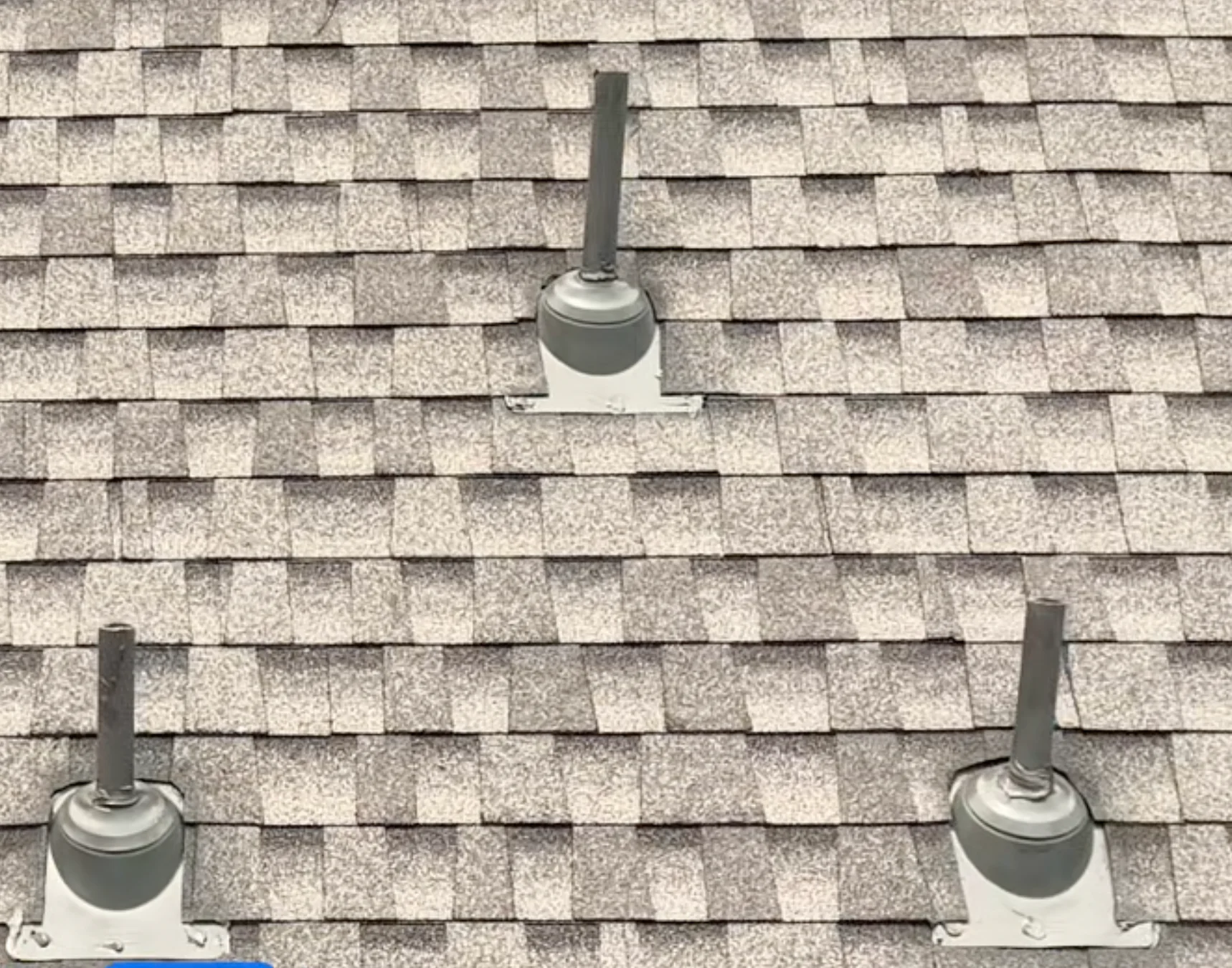 Close view of finished roof vents on a light brown shingle roof.